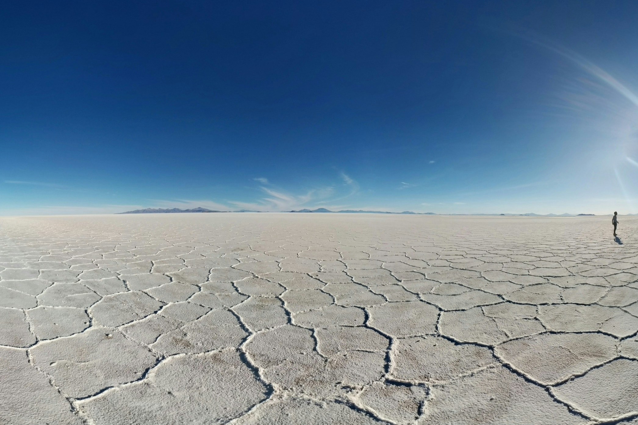 A lone figure walking across cracked desert clay